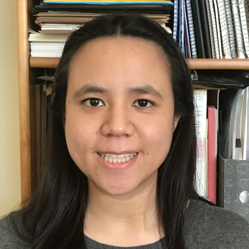 Amanda Chen is smiling and standing in front of a bookcase