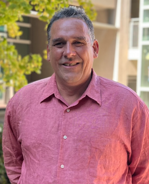  Guillermo is smiling and stands outside on Mesa campus