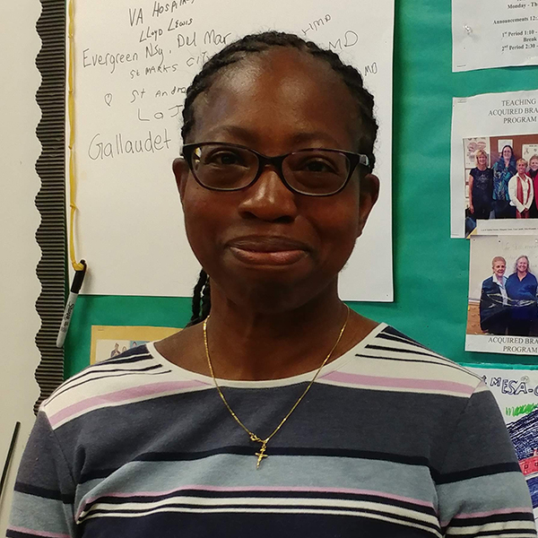 Mary smiling standing in front of a bulletin board with images and text