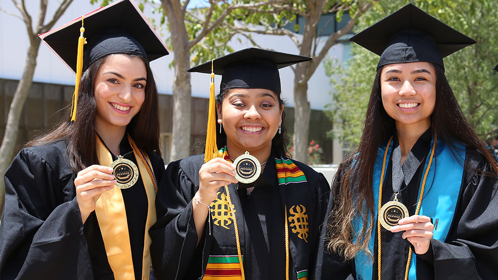 Three promise students hold promise medallions at the 2019 Miramar College commencement