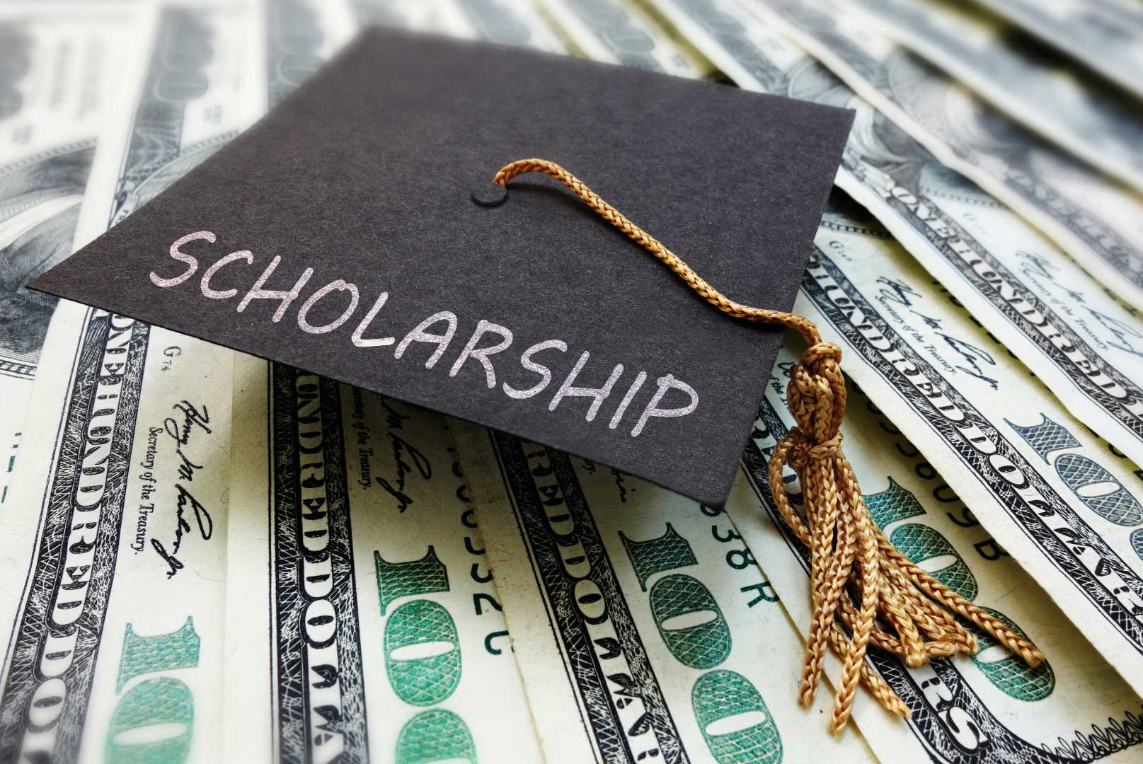 A graduation cap set on top of 100 dollar bills