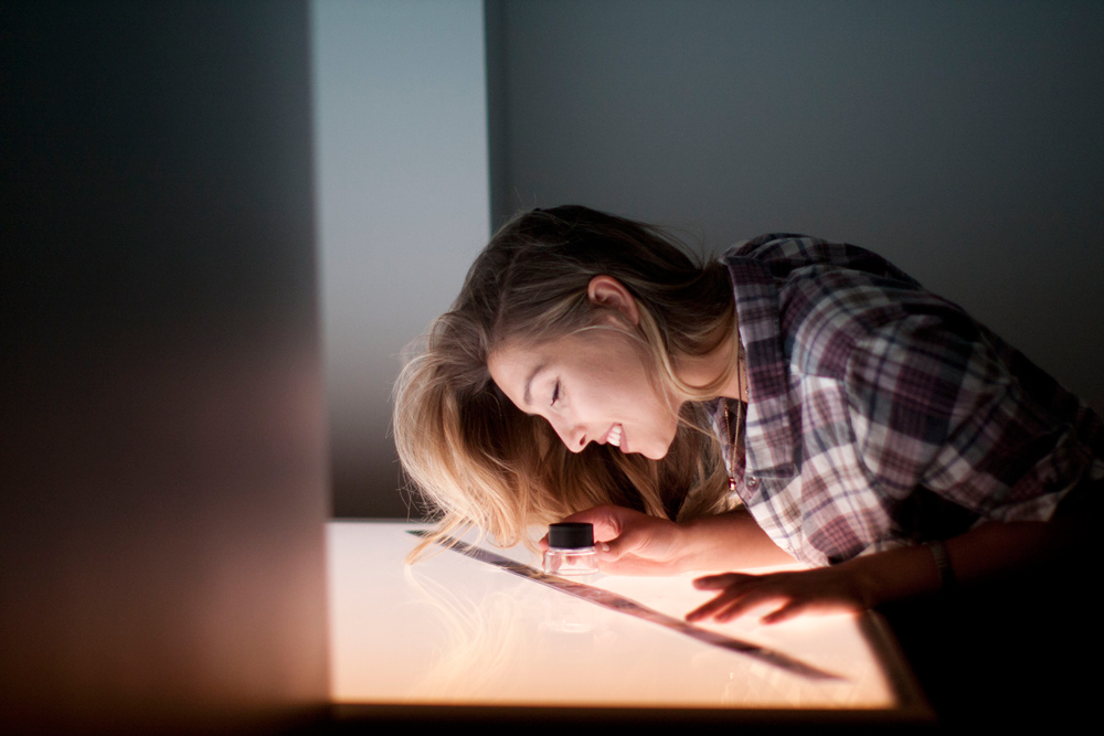 A photography student looks at negatives on a light table