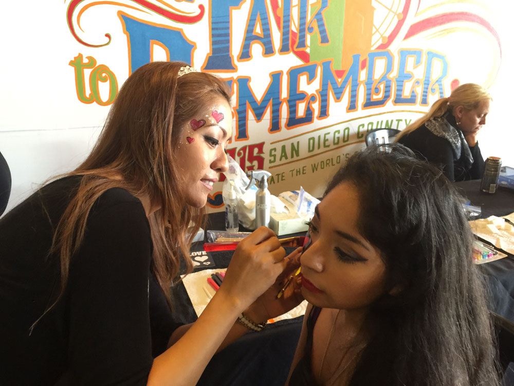 A cosmetology student puts face paint on a woman at the San Diego County Fair in 2015