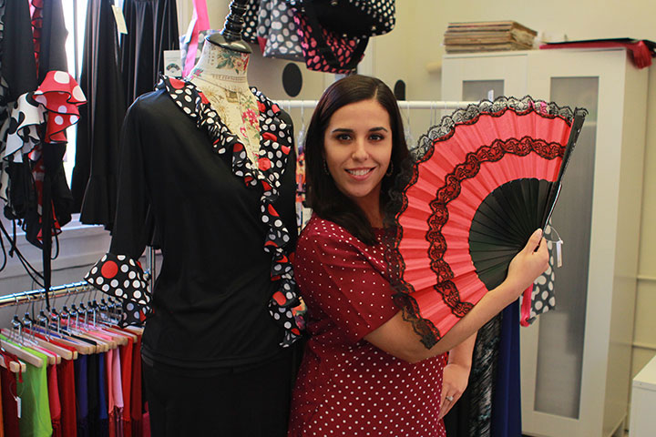 María del Mar Hinojosa poses with a flamenco dress and fan in her store The Pure Flamenco.