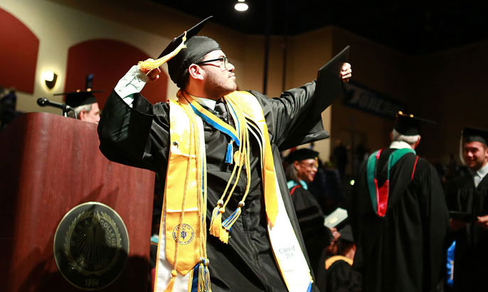 A student celebrates after receiving his diploma during Mesa College's commencement