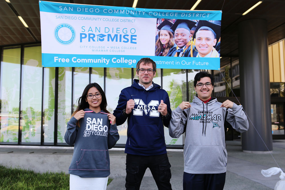 Three San Diego Promise students pose with sweatshirts from each of their campuses.