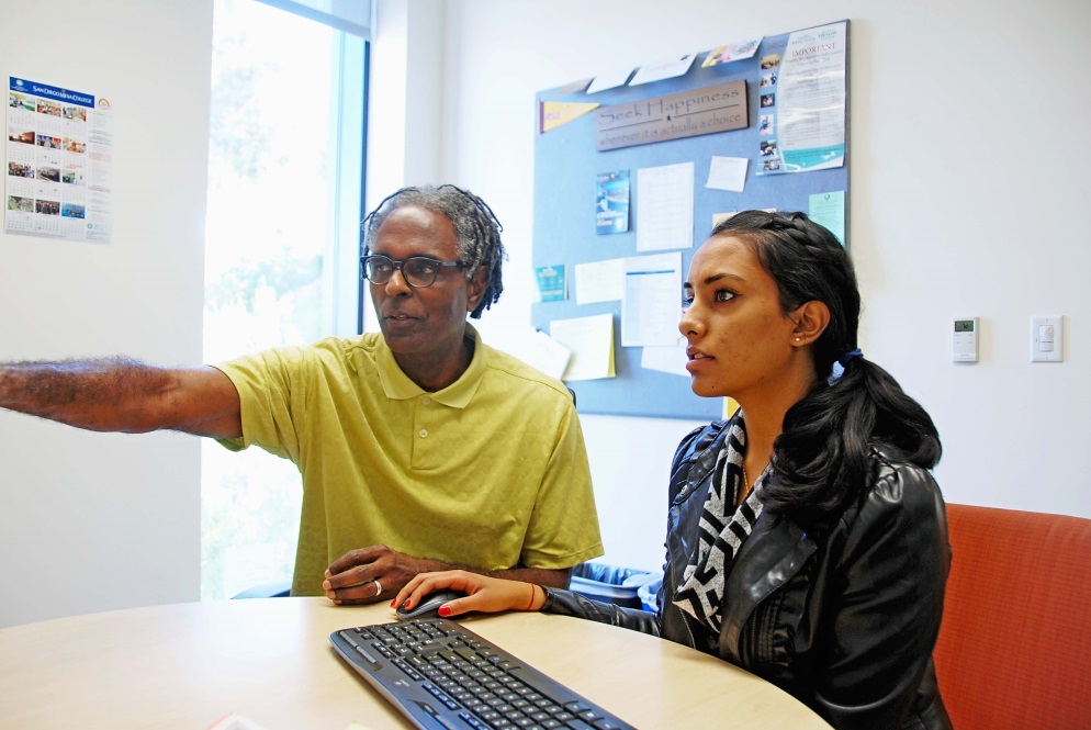 A student and a professor work on a computer.