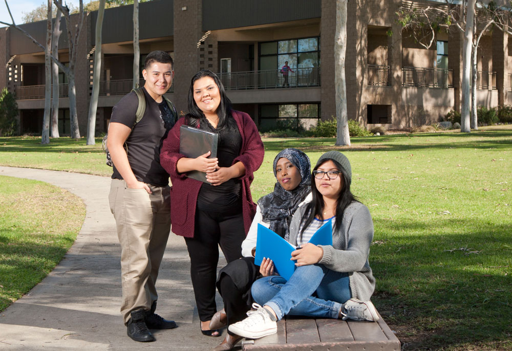 Four Continuing Education students on a bench outside near the lawn