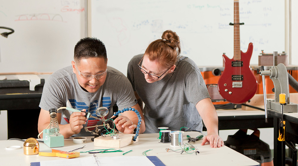 Two students work together in a guitar-building course