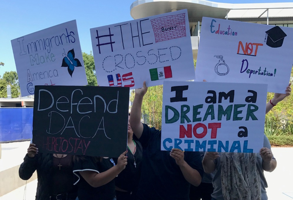 DACA students cover their faces with protest signs