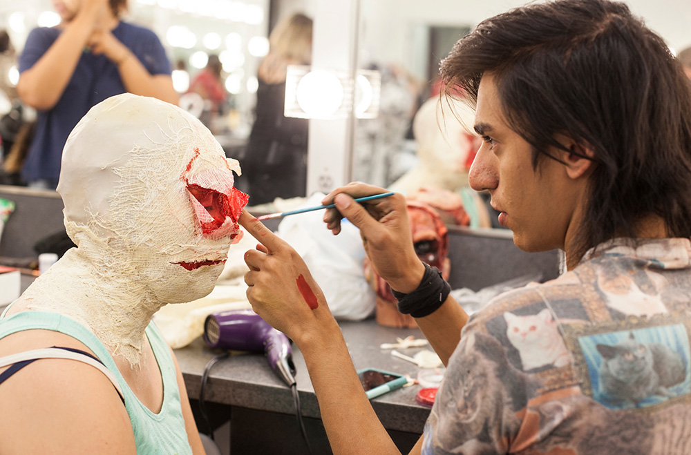 A student paints fake blood on someone's face in a special effects makeup class at San Diego City College.