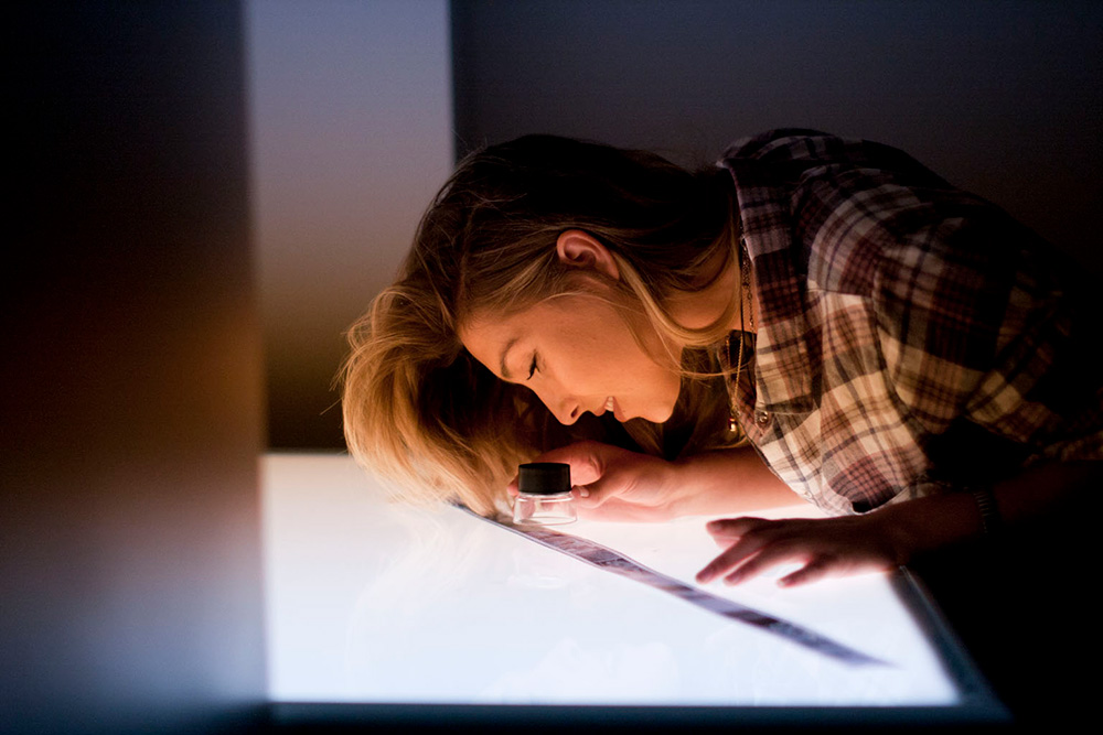 A photo student looks at negatives on a light table