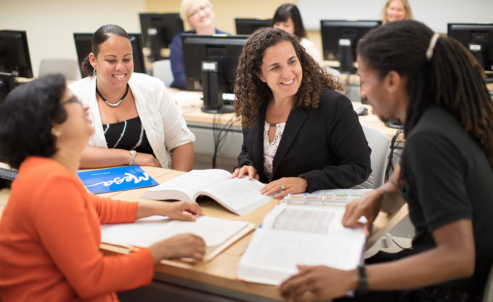 3 HIM Students and their adviser study at a table