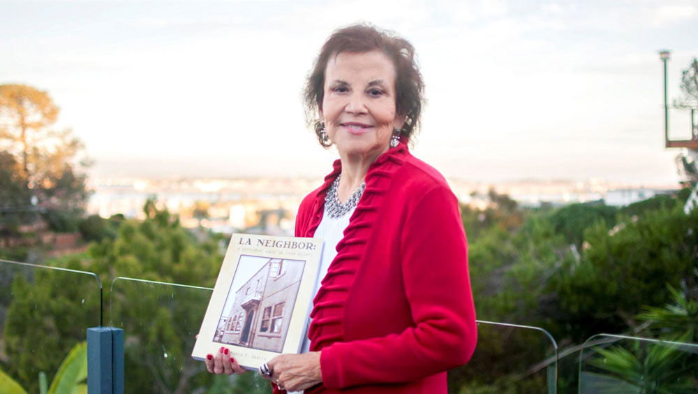 Maria Garcia holds her book La Neighborhood: A Settlement House in Logan Heights