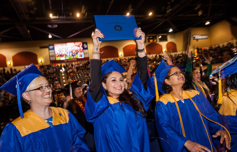 A health information management graduate holds up her diploma