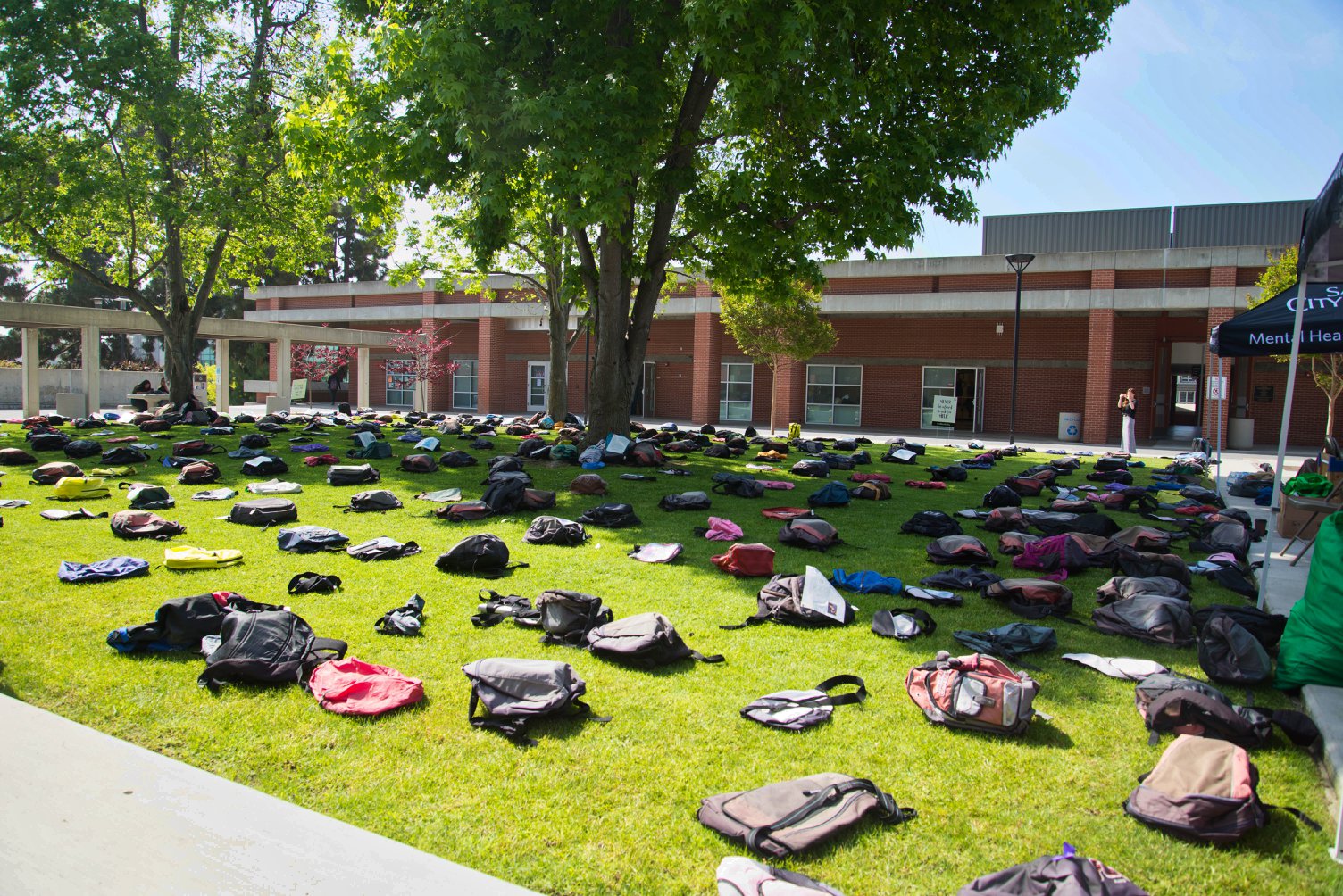 Backpacks displayed on grass during Send Silence Packing exhibit