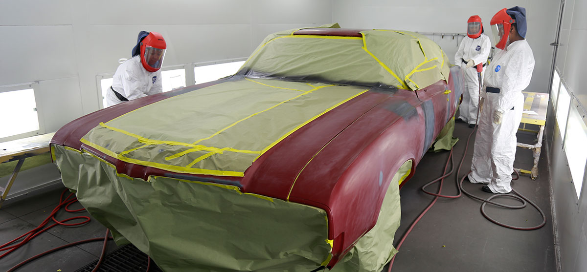 Automotive paint students prepare a car in the painting chamber.