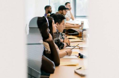 Students sit at a table in a classroom