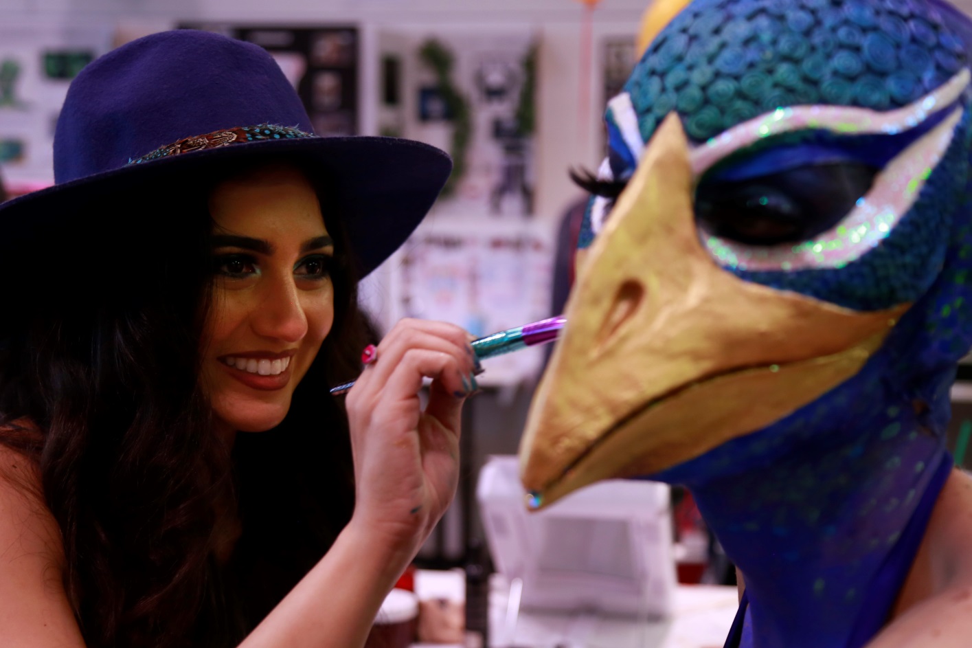 A special effects makeup student paints a bird mask