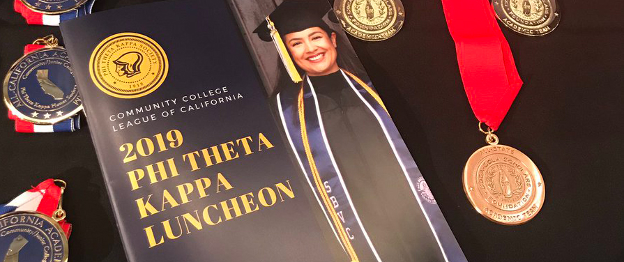 A Phi Theta Kappa luncheon brochure surrounded by medals