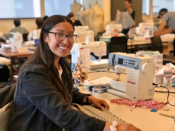 Ashley Sevilla sits next to a sewing machine