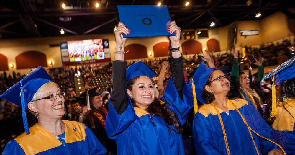 A baccalaureate graduate holds up her degree