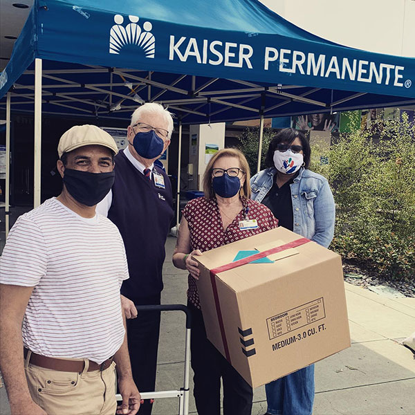 San Diego City College President Ricky Shabazz, left,  gives away a box of personal protective equipment donated by the college.