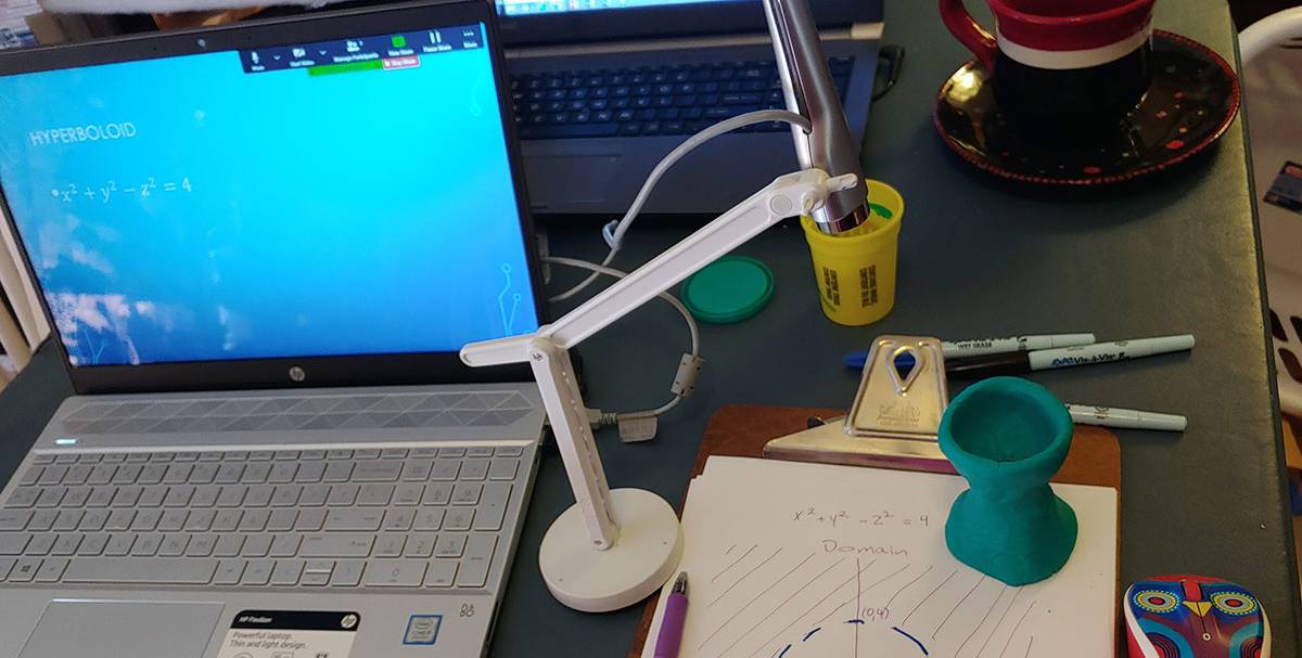 A laptop is on at a professor's work station at home