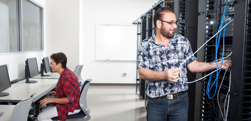 Two students work on computers and servers 