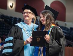 Mesa President Pam Luster hands a student her degree during commencement