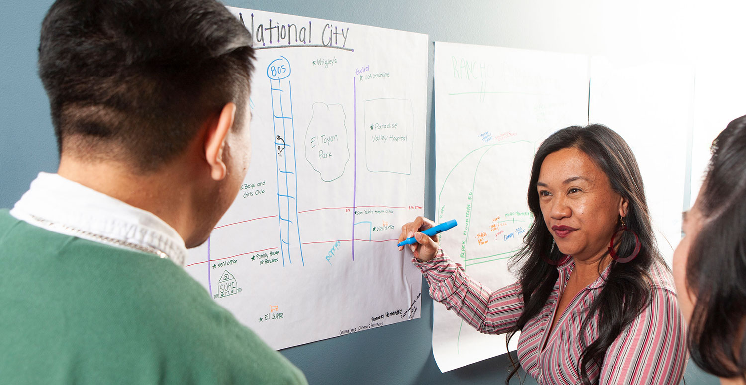 A teacher at a whiteboard talks to students