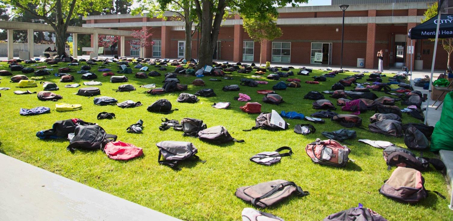 Backpacks displayed on grass at City College