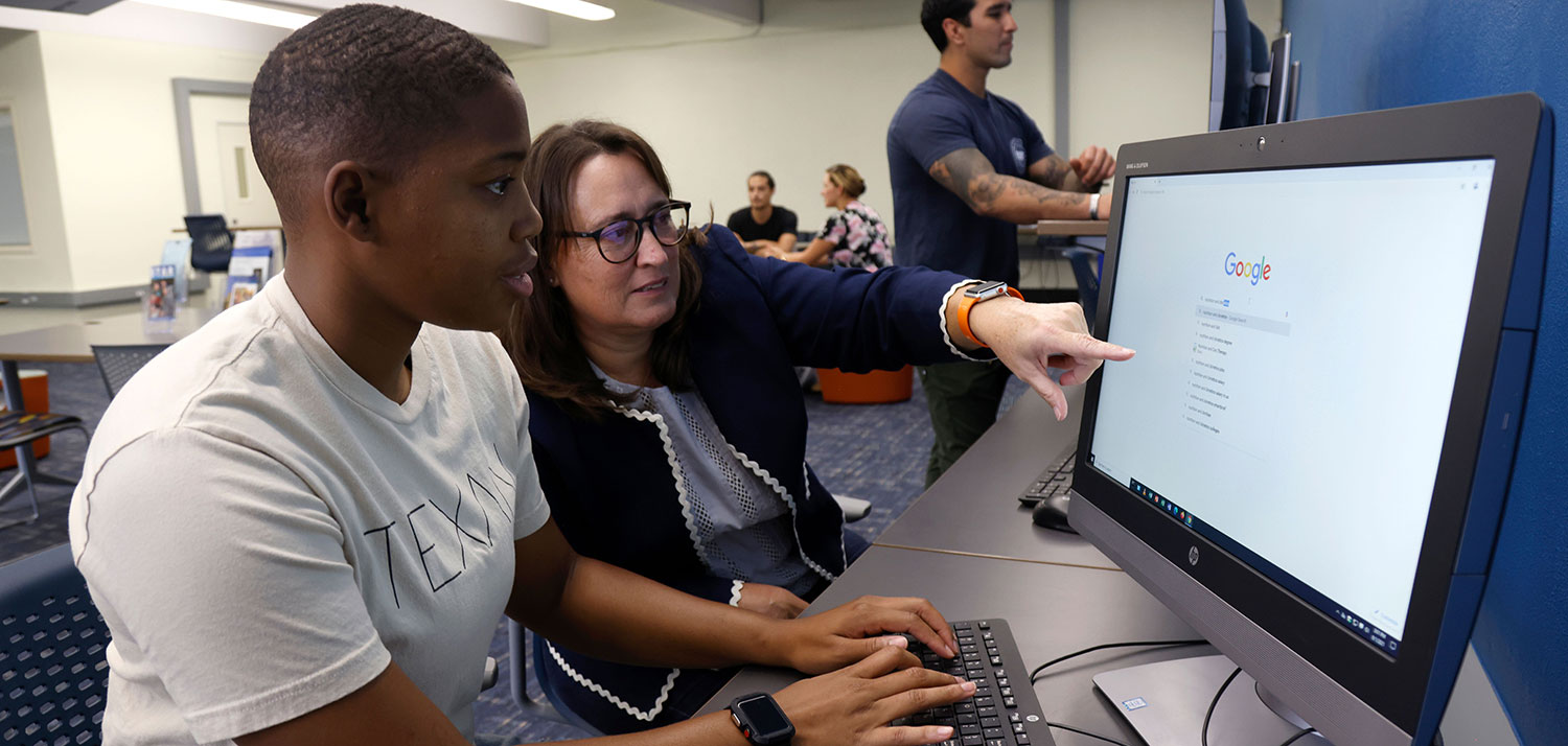 At the Veterans Center at Mesa College, Vicki Hernandez works at a computer with a student 