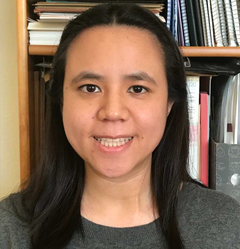 Amanda Chen is smiling and standing in front of a bookcase.