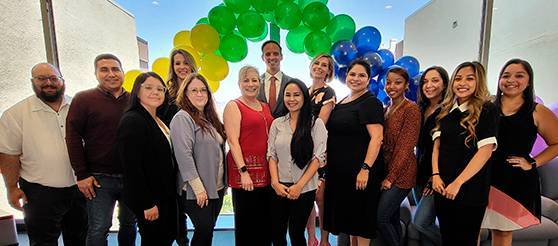 Human Resources employees take a group photo in the district office lobby. A colorful display of balloons are behind them