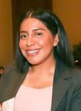 Lucia Cavallini-Martinez wears a pink shirt and a gray jacket in a portrait photo