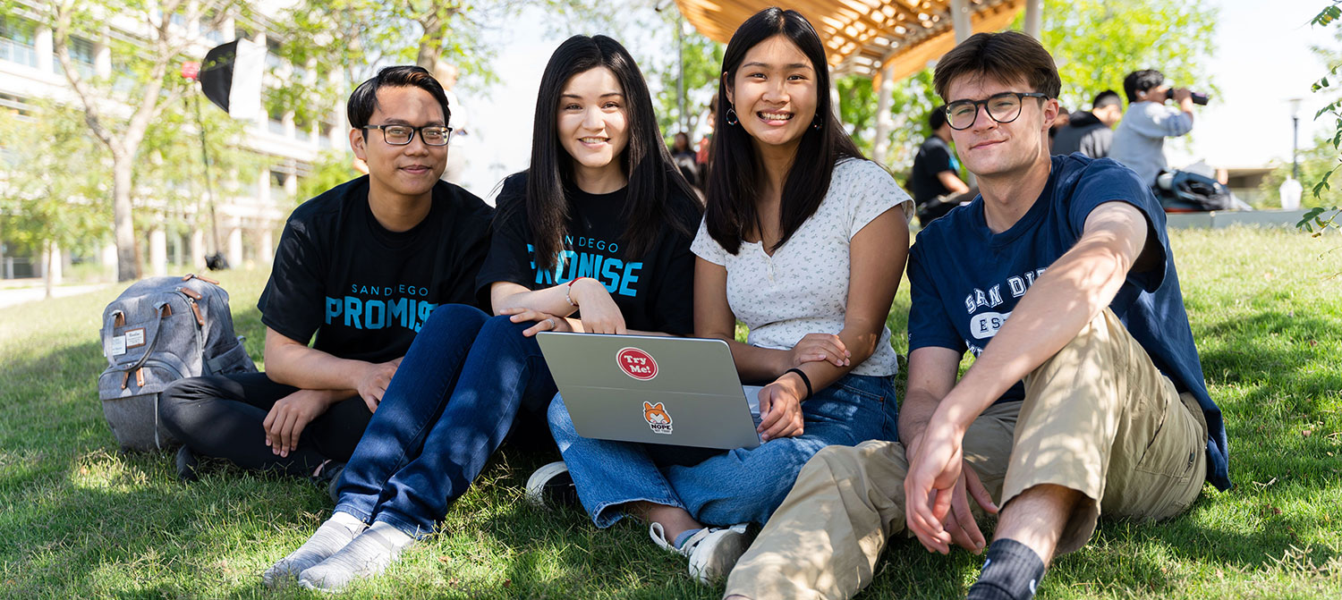 Four San Diego Promise Students sitting on the grass looking at a laptop