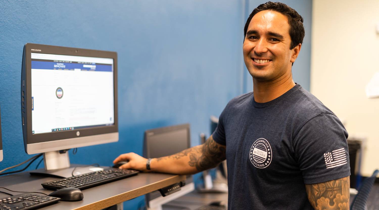 A student veteran from Mesa College works on a computer at a stand-up desk.