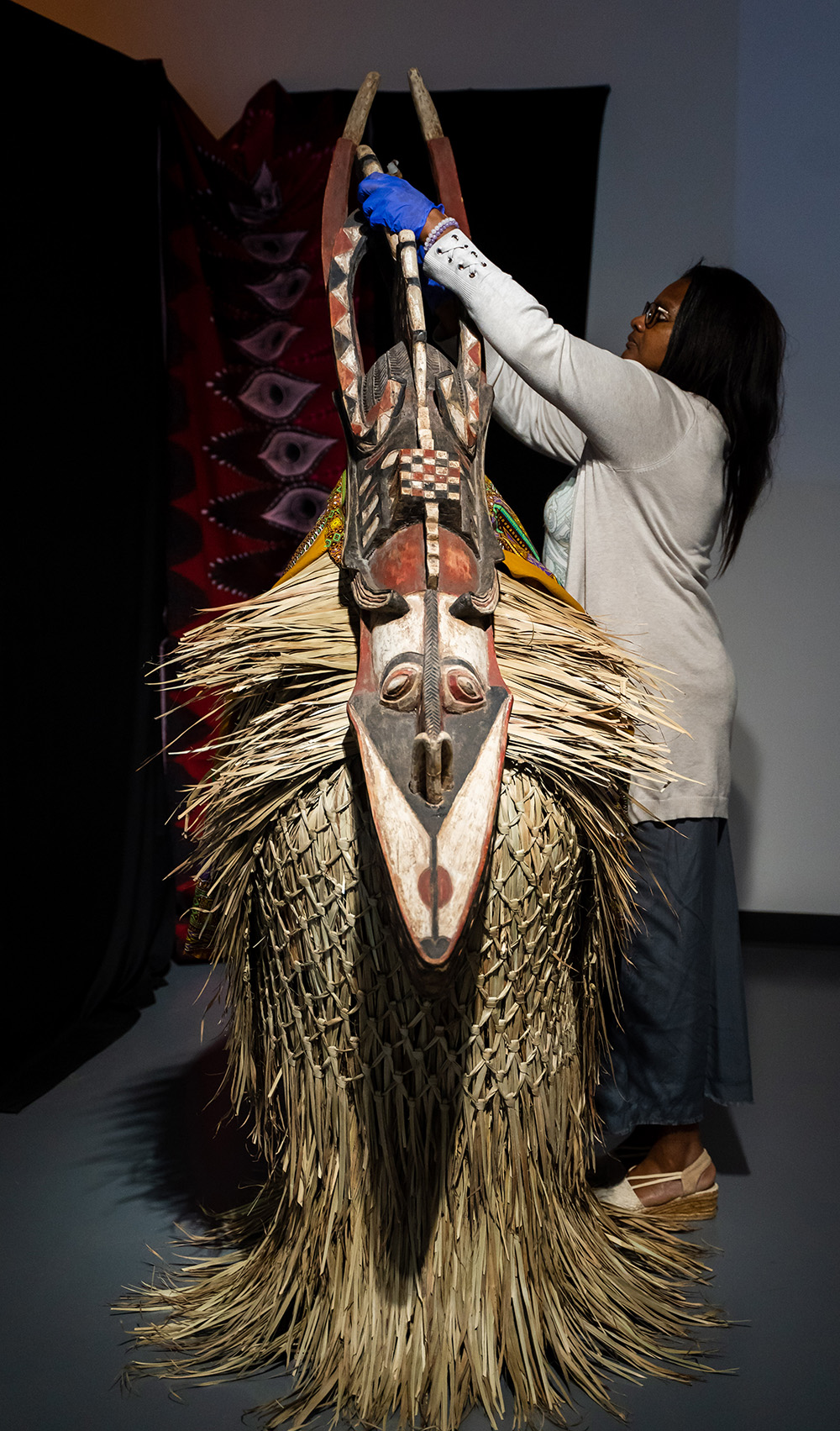 Dr. Denise Rogers adjusts a piece of art in the Africa in Context exhibit.