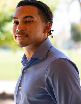 Calvin Hill wears a blue button down dress shirt.