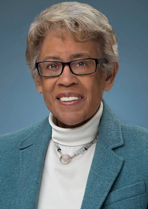 Portrait image of Constance Carroll. She is wearing a teal blazer and a white turtleneck top