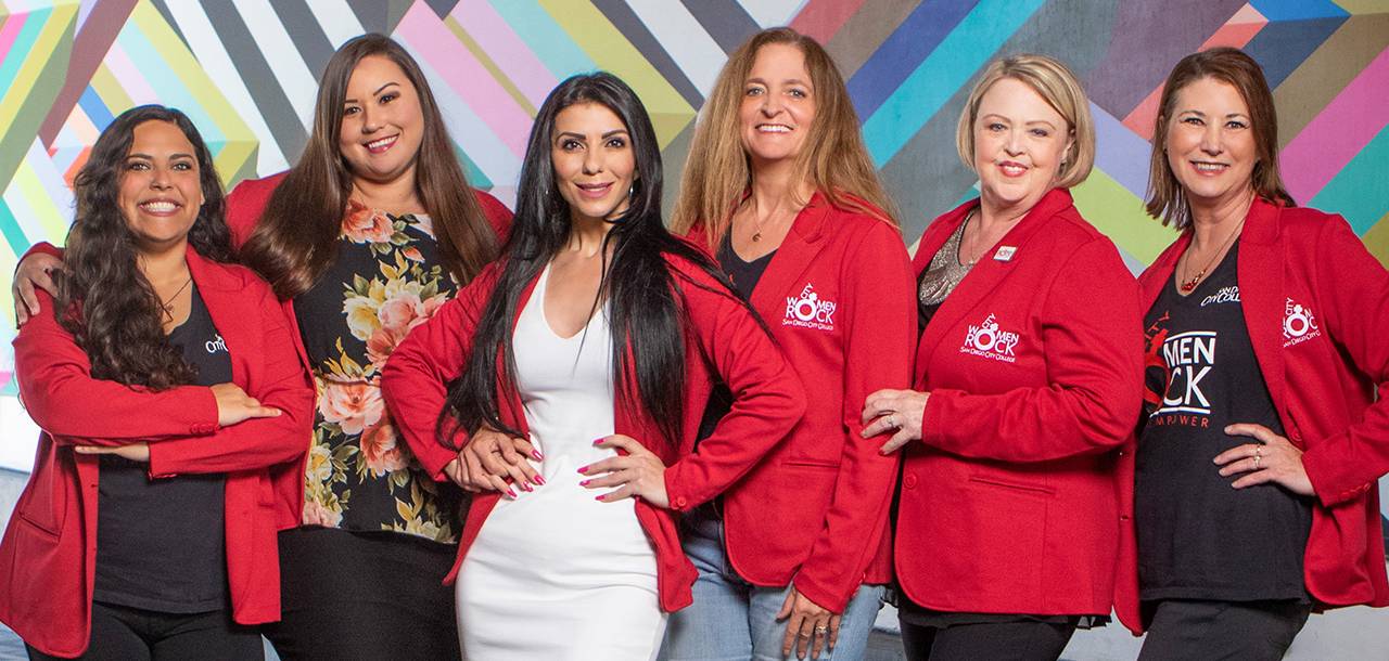 Six women wearing red blazers with the city women rock logo on them.