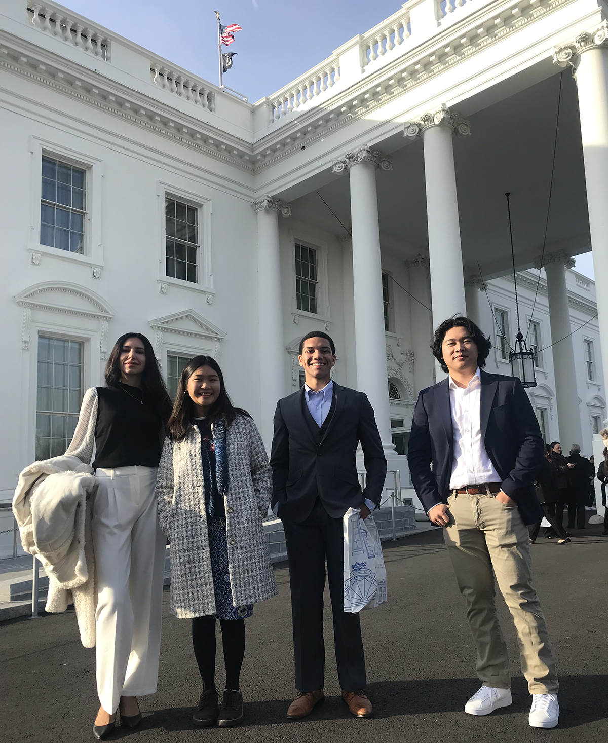 Four student trustees stand in front of the White House for a group photo
