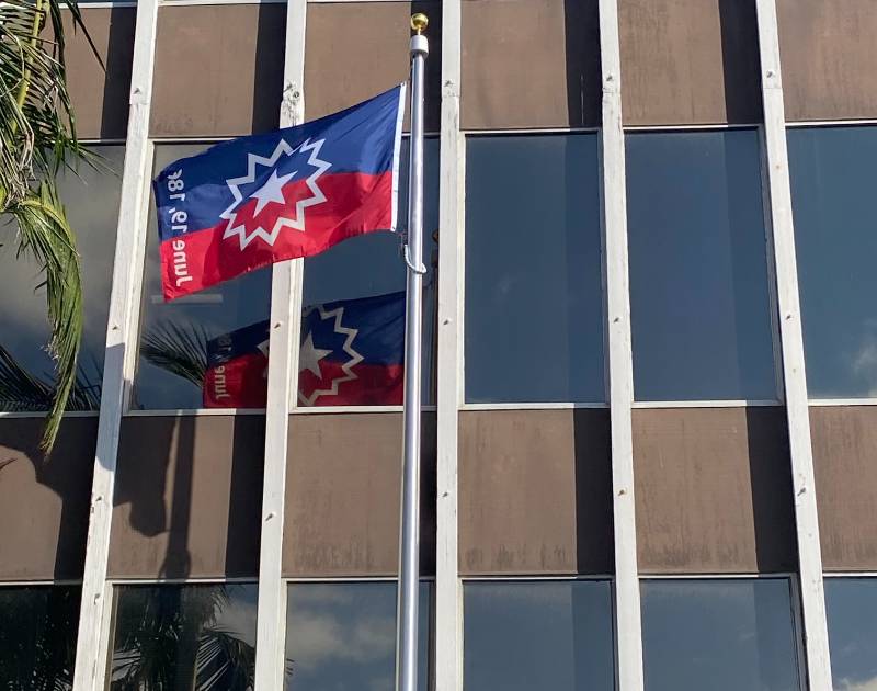 A red and blue juneteenth flag flies at the district office