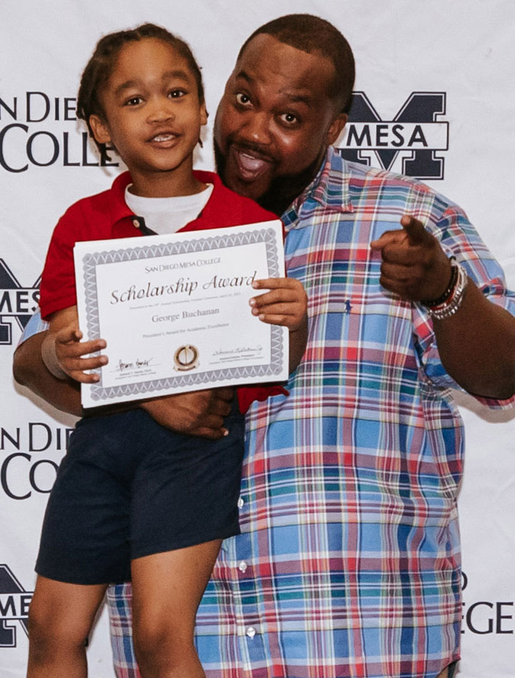 George Buchanan with his son. His son is holding up a scholarship certificate that George earned