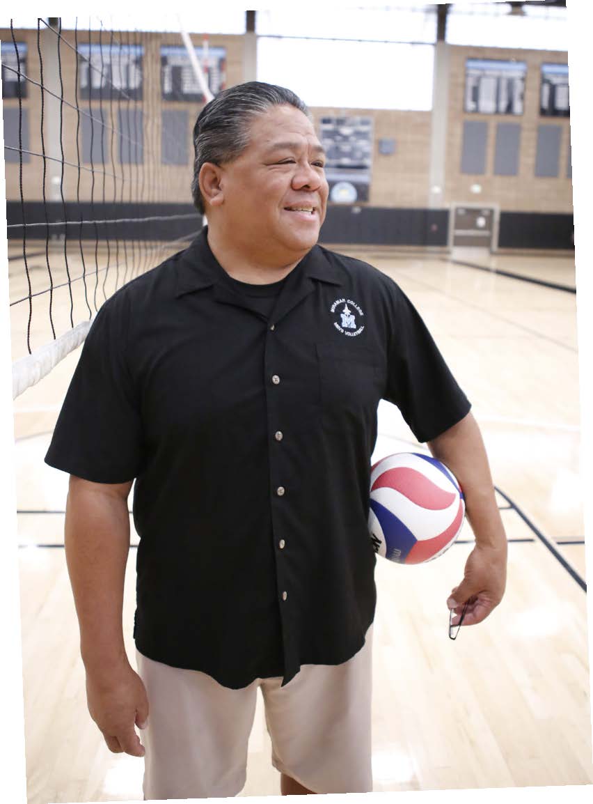 John Landicho holds a volleyball in the Miramar gymnasium. There is a volleyball net behind him