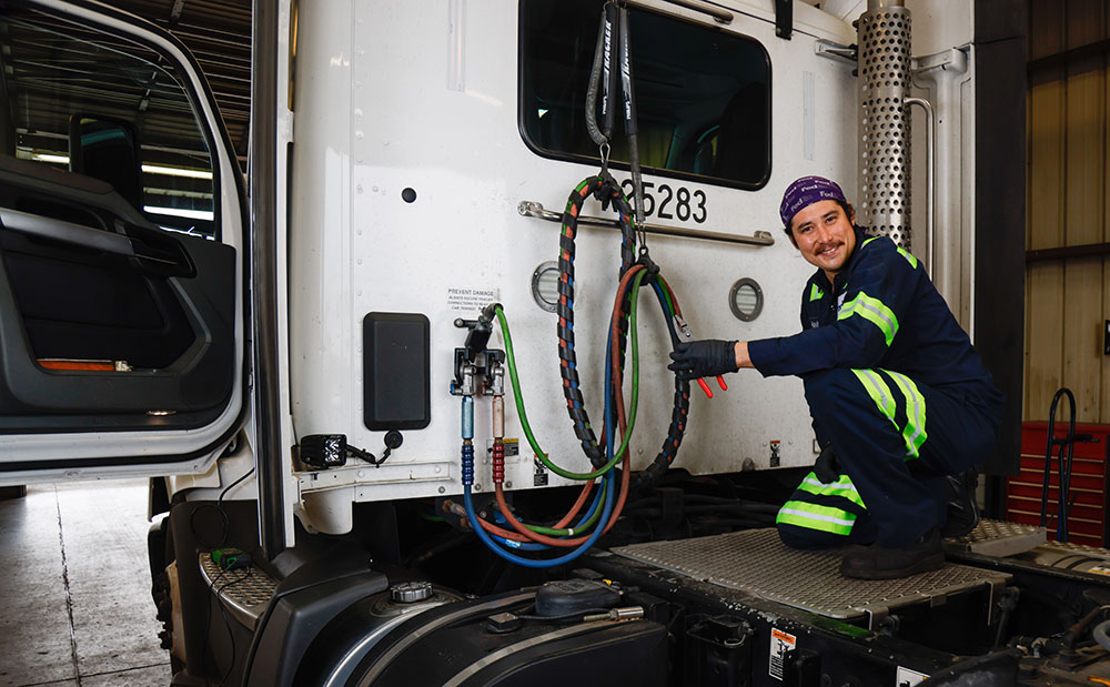 Kevin Croan kneels on the back of a diesel truck cab