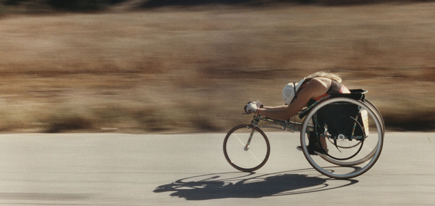 A Dan Rios photo shows a cyclist on an adaptive bicycle for people with disabilities racing down an empty street.