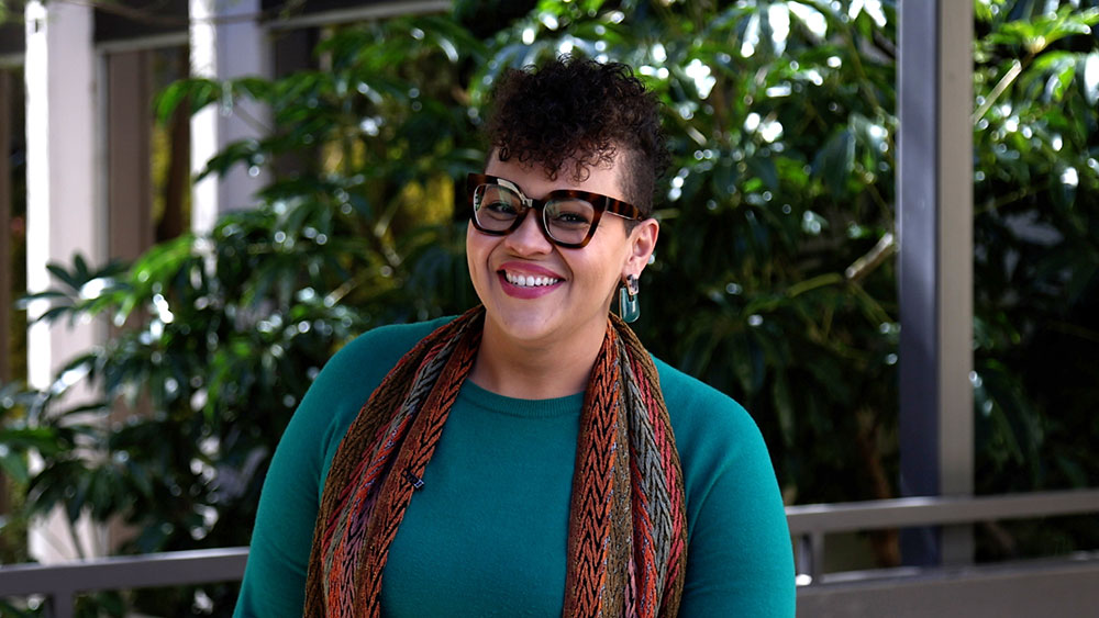 Tia Pickens wears a green top and a red and green scarf
