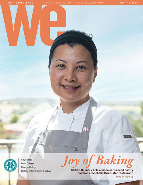 The cover of we magazine shows a woman wearing a white chefs smok and a gray apron. Text reads the joy of baking